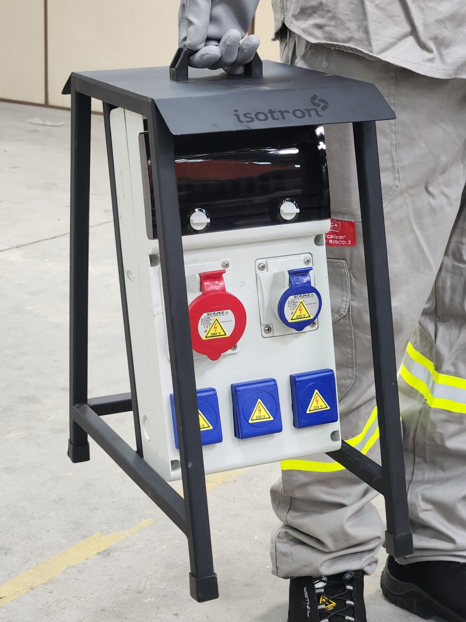 Operador carregando o quadro robô de tomadas com cavalete Isotron pelo canteiro de obras